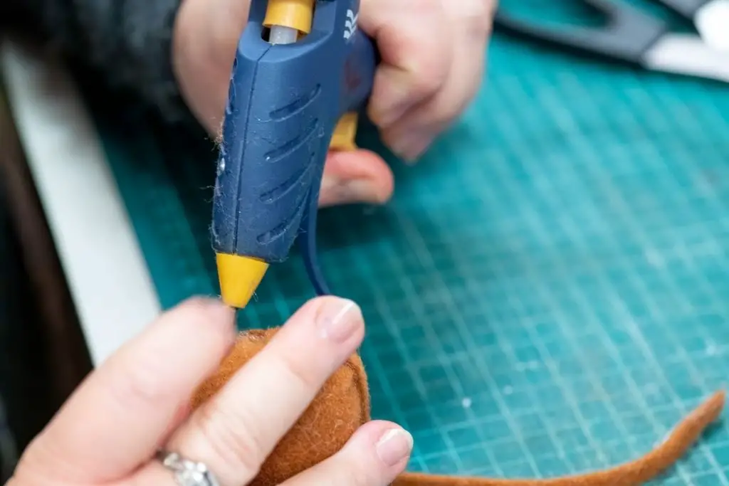 showing how do hot glue sticks work on fabric using a glue gun 